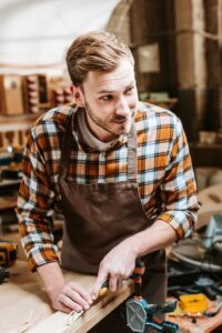 carpenter holding chisel while carving wood in workshop 200x300 1