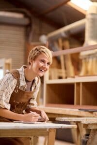 female apprentice working as carpenter in furniture workshop 200x300 1